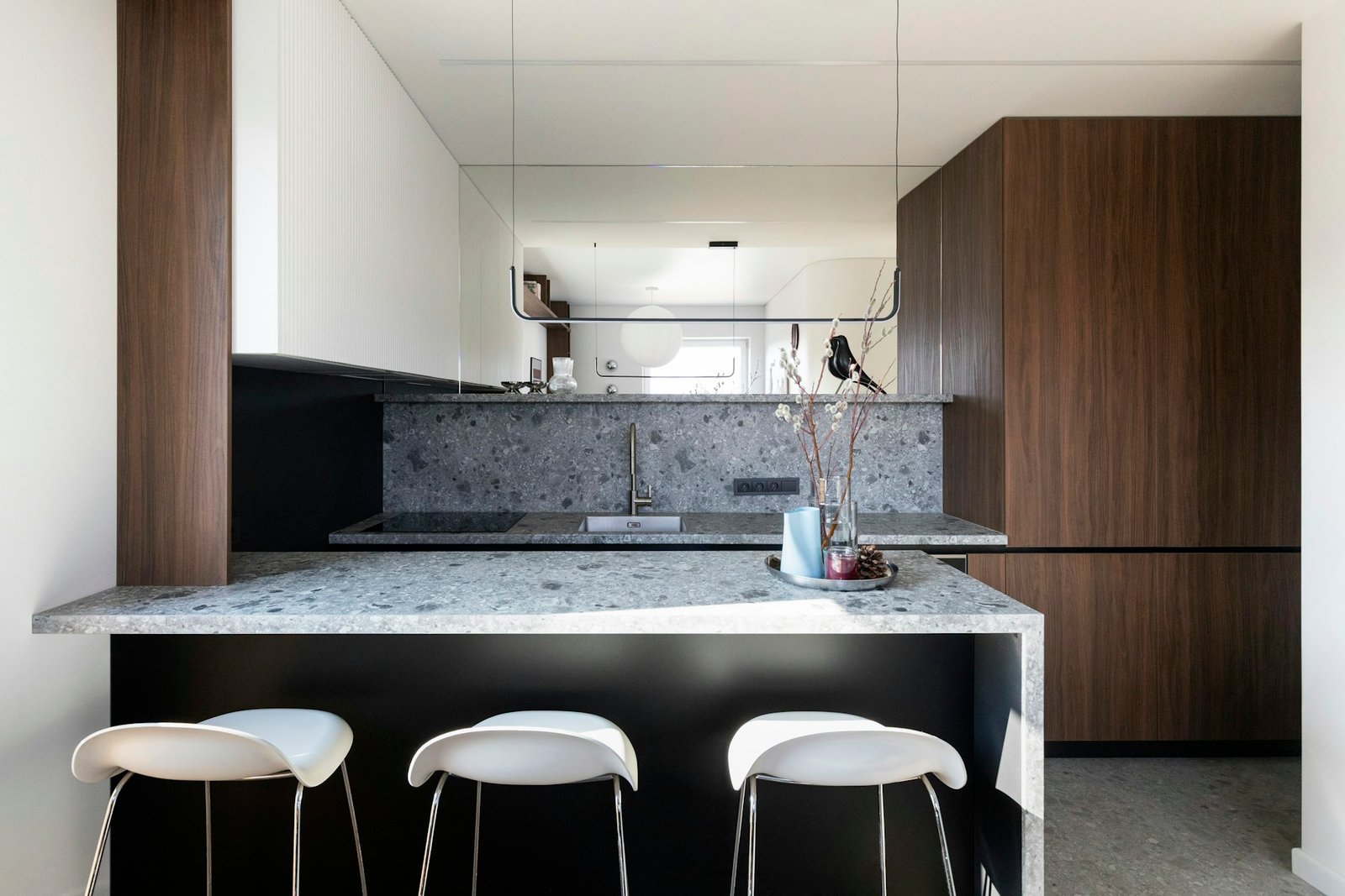 Dark walnut-toned cabinetry with a terrazzo island in a naturally lit kitchen